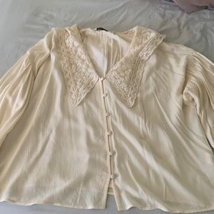 Cream top with lace collar, puff sleeves, and ruffles at the wrists